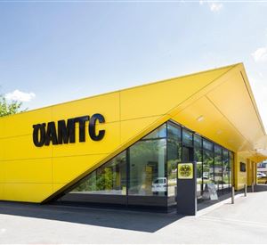 Een modern geel gebouw met grote ramen en de tekst "ÖAMTC". De architectuur is opvallend en hedendaags.