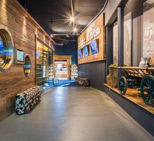 A modern hallway with wooden walls and an attractive exhibition. On the walls, pictures and information can be seen, while the lighting creates an inviting atmosphere.