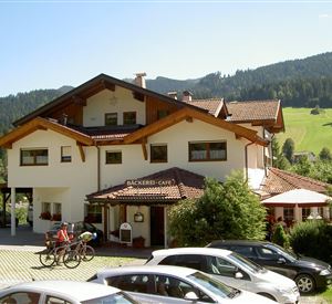 A cozy café with a charming alpine design. In the background, green meadows and forests can be seen.