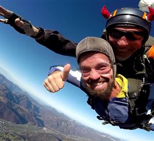 A brave tandem jump with a joking skydiver. In the background, the impressive mountain landscapes are visible.