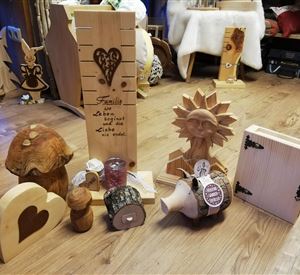 Een verzameling handgemaakte houten decoratieartikelen. Daaronder bevinden zich een hartvormig figuur, een zon, en verschillende andere sculpturen en containers.