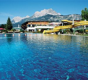Een glinsterend zwembad met een gele glijbaan en een mooi berglandschap op de achtergrond. Een ontspannende plek, ideaal voor een dag aan het water.