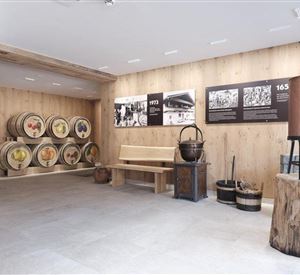 A room with wooden walls and floor, where historical barrels stand against a wall. There are seating areas and exhibits related to history.