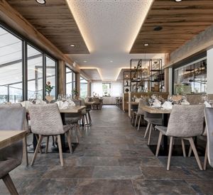 Een modern restaurant met een lichte ambiance en grote ramen. Hout- en steenelementen creëren een uitnodigende sfeer.