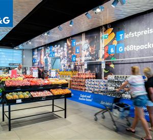 A modern supermarket with fresh fruits and vegetables on shelves. Customers are pushing shopping carts through the bright and inviting space.