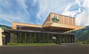 Een modern gebouw met houten bekleding en grote ramen, omringd door groene planten. De lucht is helder en blauw, en het landschap op de achtergrond is bergachtig.