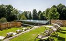A beautiful outdoor area with loungers and a modern pool.  
Surrounded by lush greenery and trees.