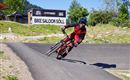 Ein Mountainbiker fährt auf einer kurvigen Strecke. Im Hintergrund ist das Schild "Bike Saloon Söll" zu sehen.
