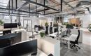 A modern office with bright workspaces and ergonomic chairs.  
Plants and large windows create a pleasant atmosphere.