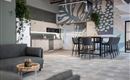 A modern office kitchenette with a large table and chairs. The walls are decorated with colorful, floral patterns.