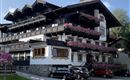 A traditional hotel building with an attractive wooden roof and spacious balconies. Colorful flowers adorn the exterior façade, giving the building an inviting charm.