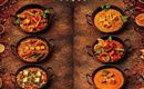 A selection of six different Indian dishes served in traditional pans. The dishes are colorfully arranged and garnished with fresh herbs.
