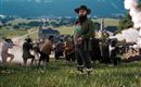 Ein Mann mit Bart und Hut steht im Vordergrund einer Landschaft. Im Hintergrund sind mehrere Personen in historischer Kleidung zu sehen, die eine Art Schießerei haben.