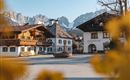 A picturesque village with traditional wooden house architectures and mountains in the background. The scenes convey a calm, alpine atmosphere.