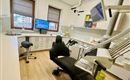 A modern dental office room with a treatment chair and a screen. The walls are bright, and there is plenty of space for medical equipment.