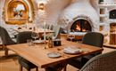 Een gezellig restaurant met een houtoven en stijlvolle meubels. De tafel is elegant gedekt en creëert een uitnodigende sfeer.