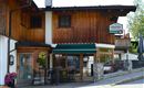 A cozy inn with a wooden facade and a terrace. Surrounded by flowers and an inviting ambiance.