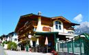 A charming building in alpine style with balconies and colorful flowers. The surroundings are clean and friendly, with a view of the mountains.