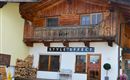 A traditional wooden house with a modern sign "STYLE EFFECT" above the front door. In the foreground, there are wood piles and a small pot with a plant.