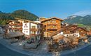 A picturesque Alpine village with traditional wooden houses and beautiful mountains in the background. The surroundings are calm and inviting.