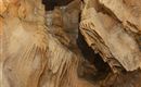 An impressive cave landscape with fascinating stalactites and stalagmites. The rocks display interesting formations and textures.