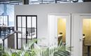 Moderne Büro-Telefonkabinen und ein verglaster Arbeitsplatz in einem hellen Co-Working-Space.