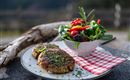 A plate with two golden-brown meatballs and a colorful salad. The salad contains fresh berries, spinach, and bell peppers.