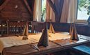 A cozy restaurant with wooden furniture and an open fireplace. The warm colors and the loving decoration create an inviting atmosphere.
