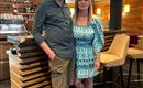 A man and a woman are standing in a modern restaurant. The decor is bright and inviting.