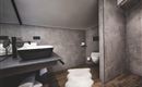 Ein modernes Badezimmer mit einem Waschbecken und minimalistischem Design. Der Boden ist aus Holz und eine gemütliche Teppichmatte liegt vor dem Waschbecken.