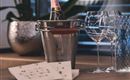 Ein eleganter Tisch mit einem Champagnerkübel, der eine Flasche Moët enthält. Daneben stehen zwei Weingläser und eine schöne Karte.