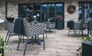 Ein stilvolles Restaurant mit einem Holzdeck und modernen Möbeln. Benötigte Pflanzen und Blumen sorgen für eine einladende Atmosphäre.