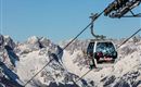 A cable car travels over snow-covered mountains. The clear sky and the majestic peaks create an impressive winter landscape.