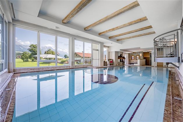An elegant indoor pool with large windows that offer a view of the mountains. The space has a modern atmosphere and plenty of natural light.