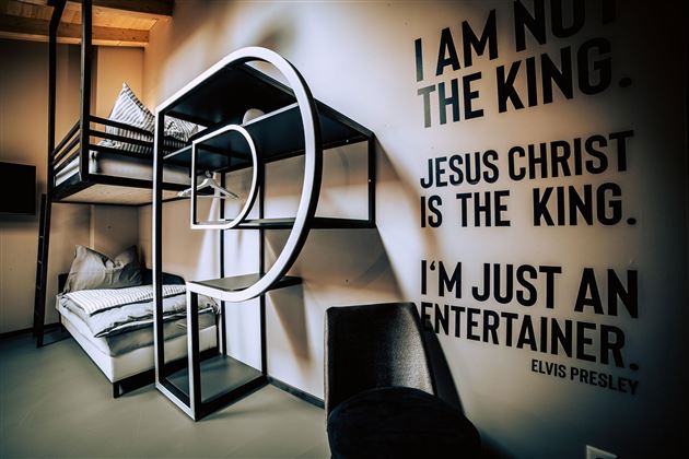 A modern room with a loft bed and minimalist decor. On the wall are quotes that remind one of Elvis Presley.