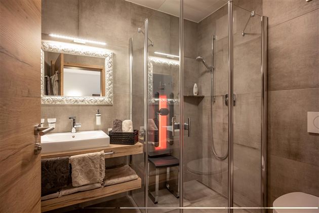 A modern bathroom with a glass shower and light wood details. The mirror and the sink faucet create a stylish atmosphere.