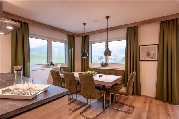 Modern dining room with a wooden table and stylish chairs. Large windows let in plenty of light and offer a view of the landscape.