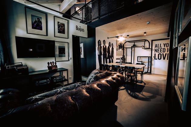 Ein stilvolles und modernes Wohnzimmer mit einem Ledersofa und einem Esstisch. An der Wand sind Bilder und ein inspirierendes Zitat zu sehen.