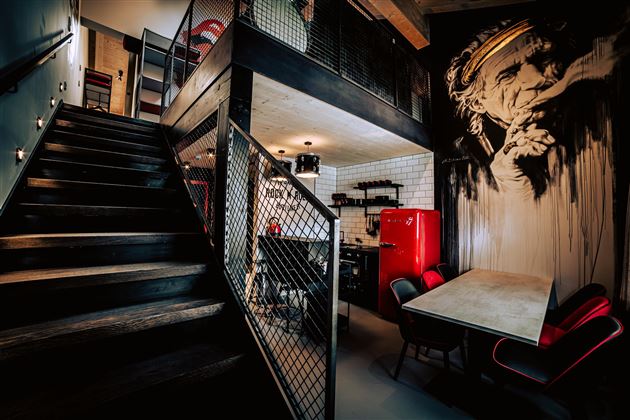 A modern, stylish interior view with a staircase and an open kitchen. An impressive mural is located on the wall.