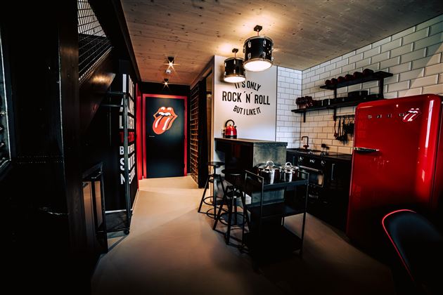 Eine moderne Küche mit einem roten Kühlschrank und stylischem Zubehör. An der Wand befindet sich ein auffälliges "Rock 'n' Roll"-Motiv.
