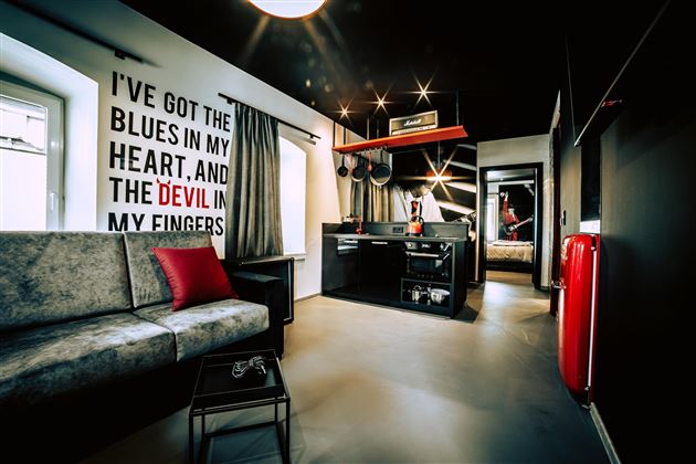 A modern room with a sofa and a small kitchenette. On the wall is a creative saying in large letters.