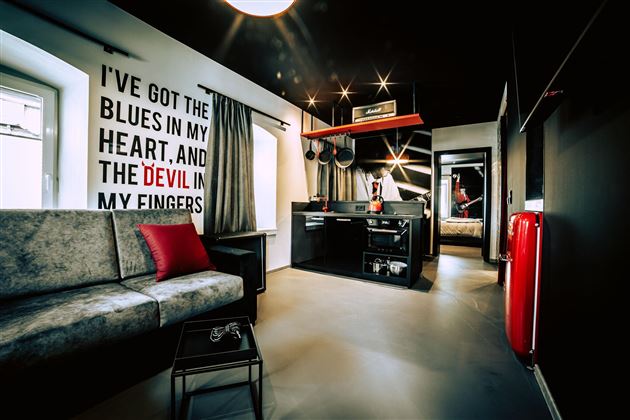 Ein modernes Zimmer mit einem gemütlichen Sofa und einer Küchenzeile. An der Wand steht ein auffälliger Schriftzug, der Atmosphäre schafft.