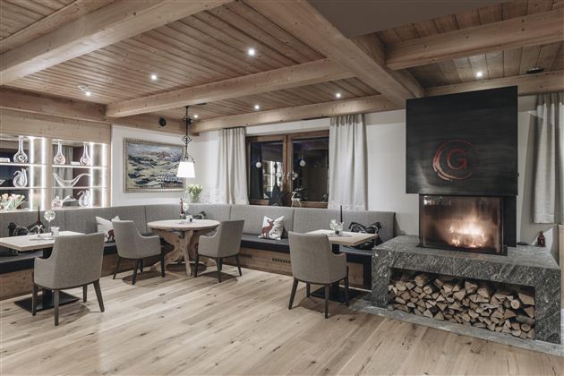 A cozy restaurant with wooden decor and a modern fireplace. The tables are elegantly set, creating an inviting atmosphere.