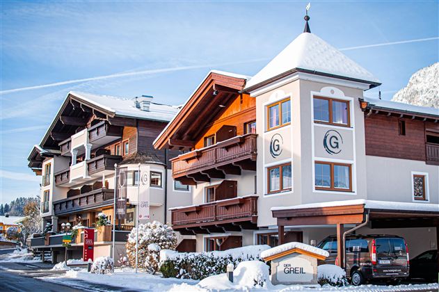 A charming building in Alpine style, surrounded by snow. The façade is bright and friendly, ideal for a winter stay.