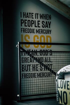 A modern room with a wall displaying text written in English. The text focuses on Freddie Mercury and contains a strong personal opinion.