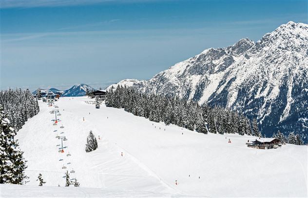 A dreamy winter landscape with snow-covered mountains and a ski resort. The surroundings are calm and inviting for winter sports enthusiasts.