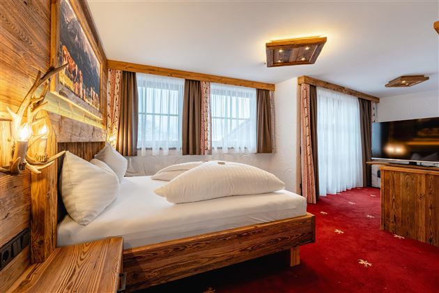 A cozy bedroom with wooden paneling and two beds.  

Large windows provide plenty of daylight, and a modern TV corner is also available.