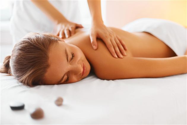 A relaxed woman is receiving a back massage. She is lying on a table and enjoying the treatment.