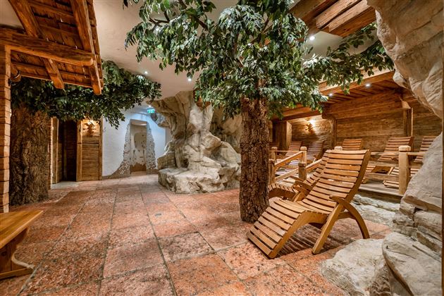 A relaxing wellness area with wooden furniture and artificial trees. Gentle lighting creates a calm atmosphere.