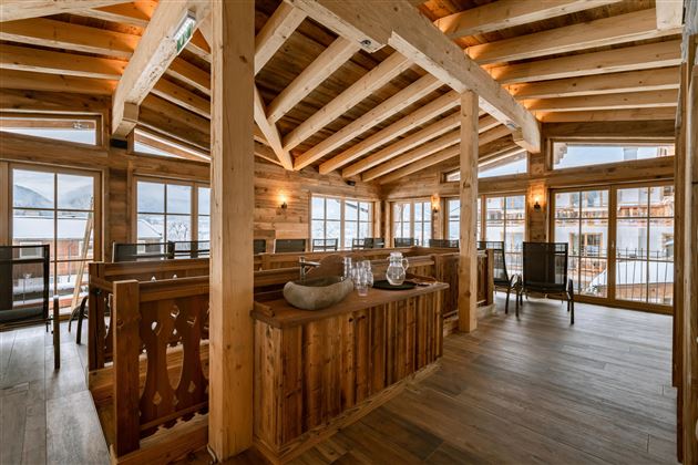 A cozy restaurant with wooden ceilings and large windows. The decor is rustic and inviting.